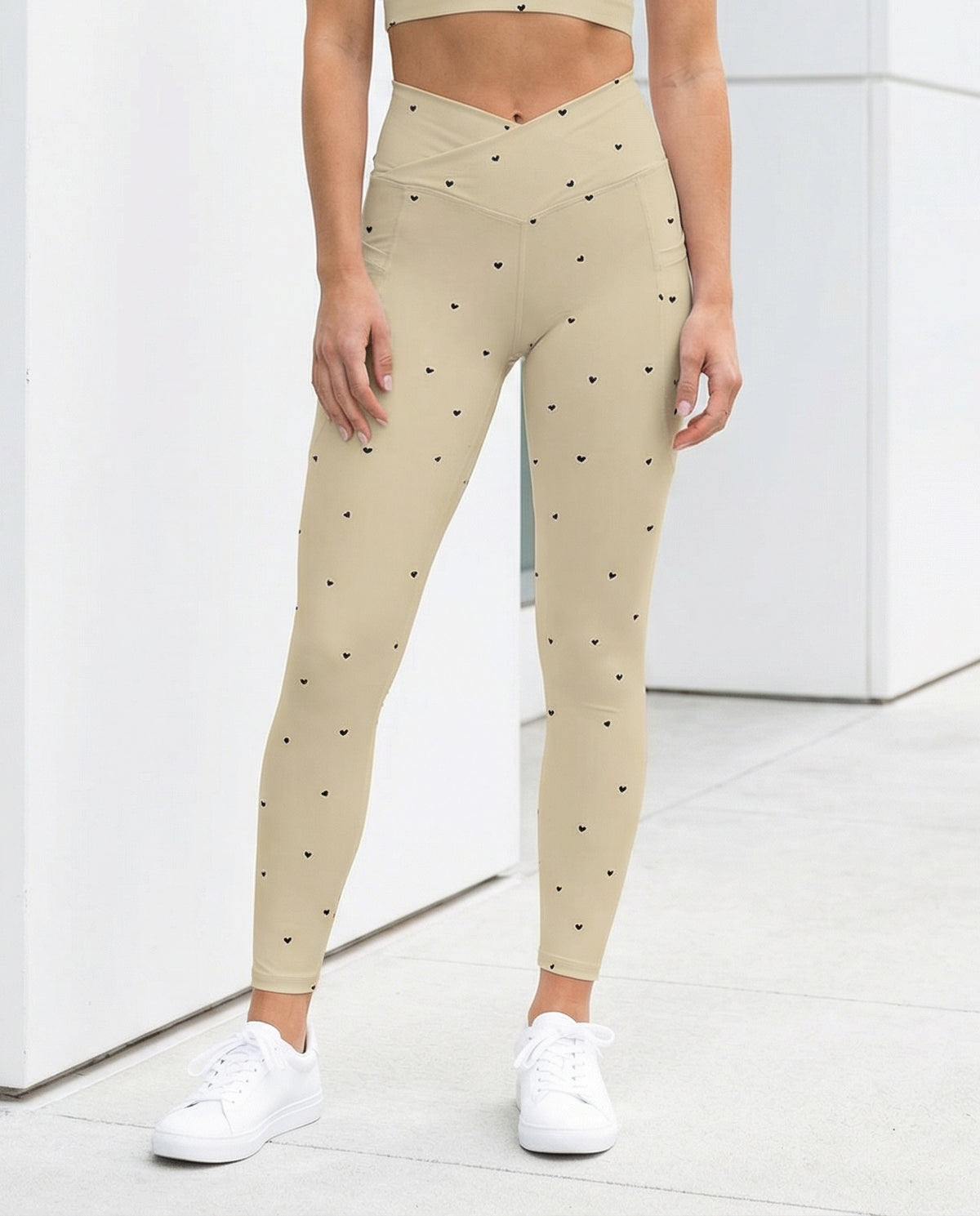 woman wearing Beatrix cream beige crossover leggings with pockets and tiny black heart print front