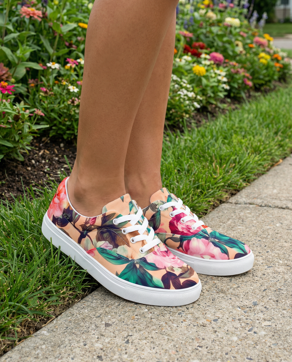 Woman wearing coral low-top sneakers with white laces with coral color and teal and pink floral botanical feminine pattern showing the shoes at an angle from the front
