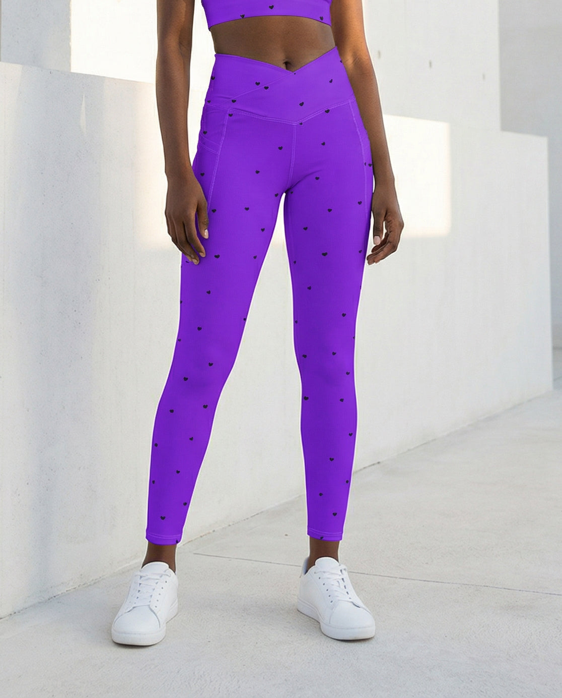 woman wearing Jillian vivid violet purple crossover leggings with pockets and tiny black heart print front