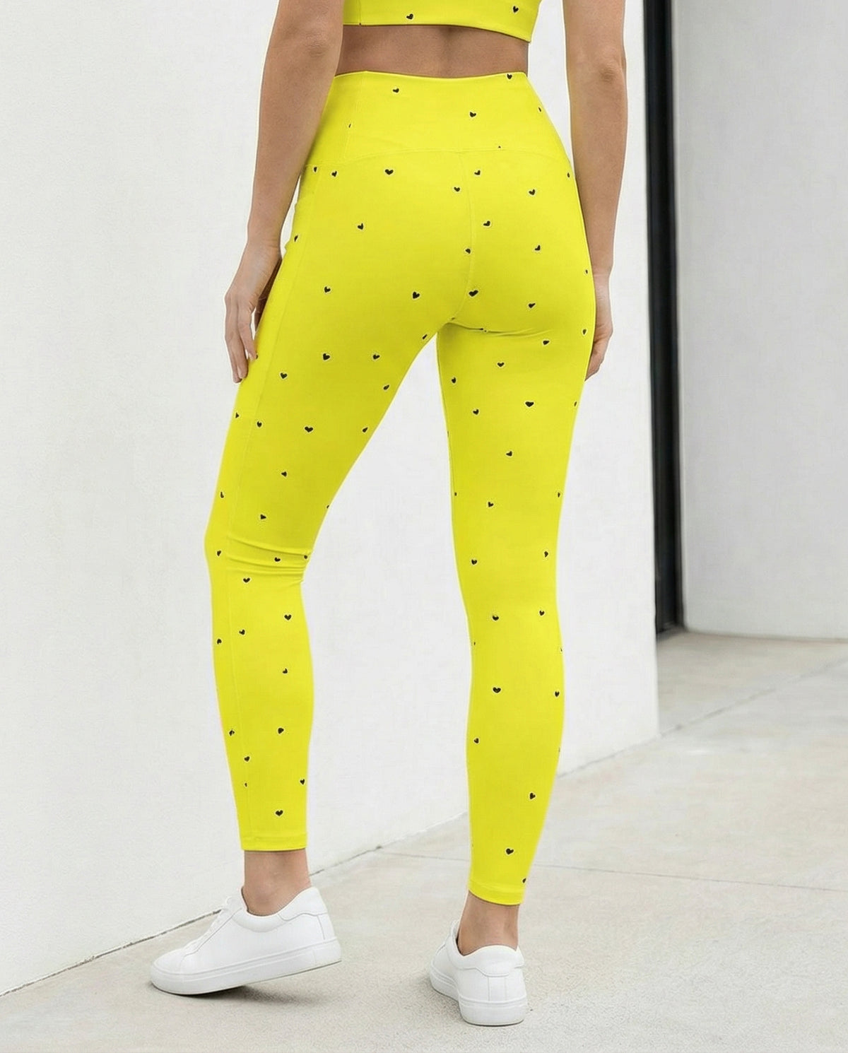 woman wearing Virginia neon yellow crossover leggings with pockets and tiny black heart print back