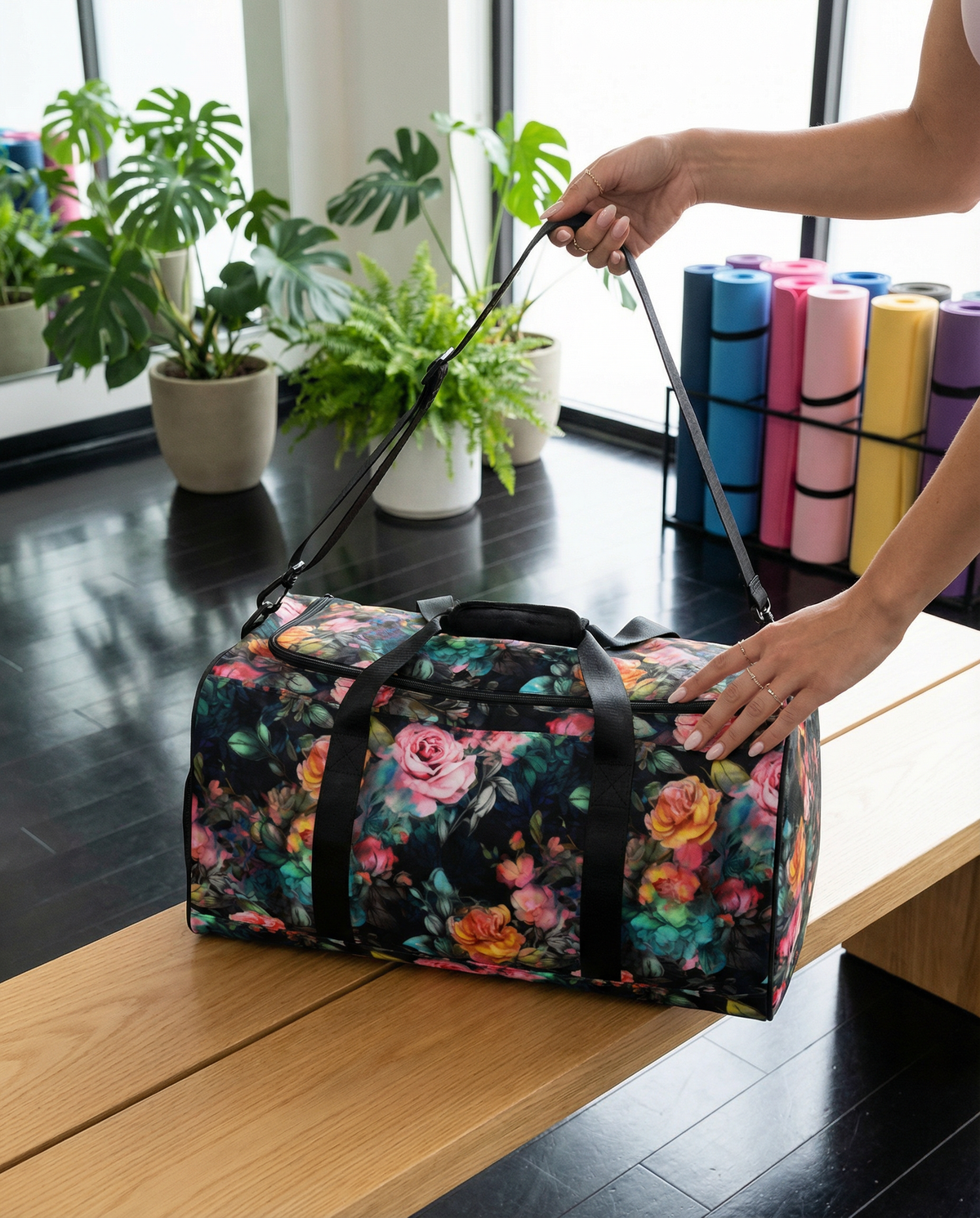 Full size black duffle bag with black handles and removable black shoulder strap and zipper enclosure with vivid rose feminine botanical floral pink yellow and teal pattern showing the front